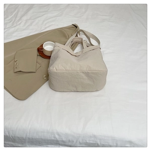 Détail d'un sac cabas beige minimaliste avec tissu texturé doux et large bandoulière