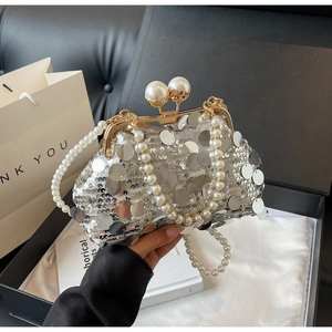 Macro shot of silver sequin evening bag with gold frame and large pearl clasp detail