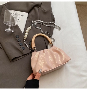 Sac à main plissé rose avec poignée en bois, texture encre dorée et détail chaîne perles