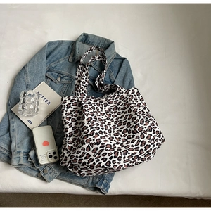 Detailed macro shot of large leopard print canvas tote bag on denim jacket background