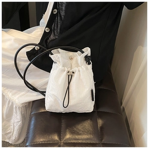 Detail of white nylon drawstring bucket bag featuring subtle checkered texture and silver hardware