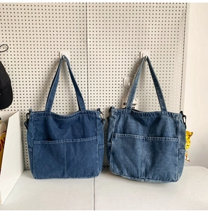 Vista dettagliata di borse tote in denim blu scuro e chiaro con tasche frontali e anelli