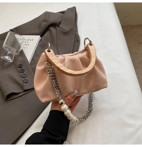 Détail du sac plissé rose clair avec poignée en bois et bandoulière en perles