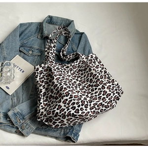 Detail of large leopard print tote bag placed on denim jacket for a stylish daily look