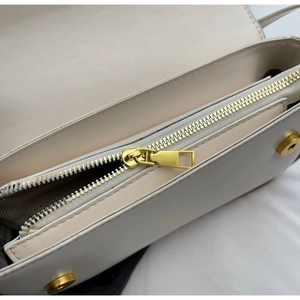 Detail van de crèmekleurige lederen tas met gouden rits en getextureerde voering