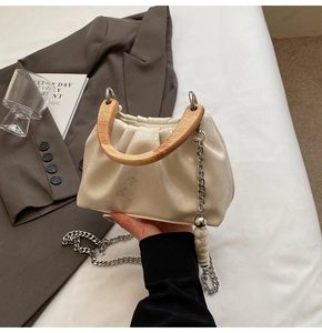 Détail du sac seau plissé crème avec poignée en bois et bandoulière en perles et métal