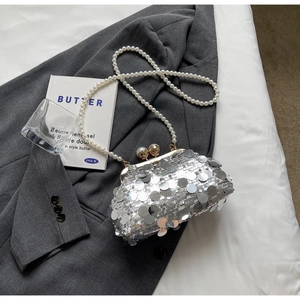 Close-up of silver sequin evening bag with pearl strap on a luxury blazer backdrop