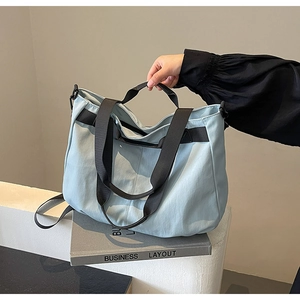 Detailed side view of light blue tote bag with reinforced black canvas straps