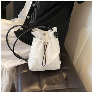 Detail of white nylon drawstring bucket bag with micro-grid texture and leather strap