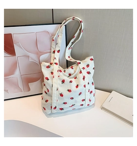 Detail of strawberry print corduroy tote bag showing its soft ribbed texture and dual straps