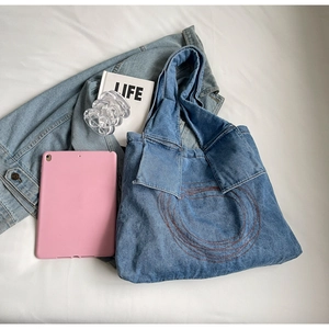 Flat lay of blue denim tote bag with circular stitching and casual lifestyle props