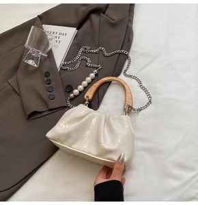 Détail du sac seau plissé blanc avec poignée en bois et bandoulière en perles nacrées