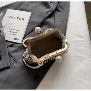 Detail of luxury sequin evening bag with large pearl clasp on grey blazer background