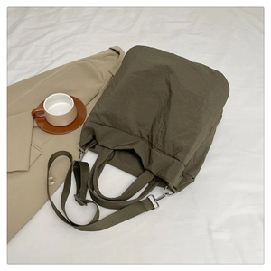 Grand sac cabas vert armée avec bandoulière réglable sur un tissu blanc doux