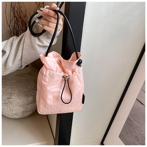 Detailed macro view of pink drawstring bucket bag with black strap and checkered texture
