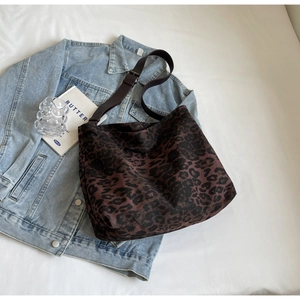 Close-up of leopard print canvas tote bag with adjustable wide strap on denim