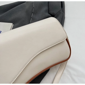 Detail van de crème schoudertas met bruine biezen en gladde kunstlederen afwerking