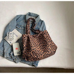 Flat lay of leopard print tote bag with denim jacket and daily essentials for travel