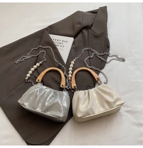 Détail de sacs plissés avec poignées en bois et bandoulières en perles argent et crème