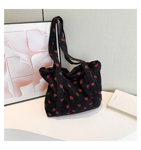 Detail of strawberry print on black corduroy tote bag with soft fabric texture