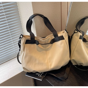 Detail view of cream canvas tote bag with black wide straps and crossbody functionality