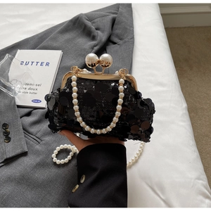 Detail of black sequined clutch bag with pearl handle and metal clasp for formal dresses