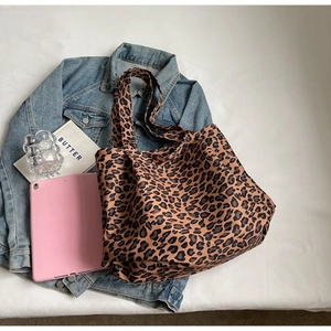 Detail of leopard print tote bag placed with a denim jacket and lifestyle accessories