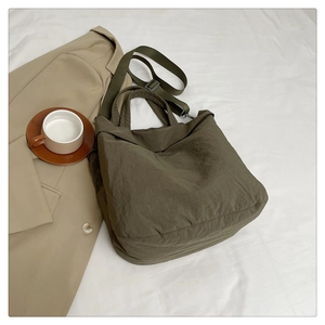 Détail d'un grand sac fourre-tout en nylon vert armée sur fond lifestyle neutre et élégant