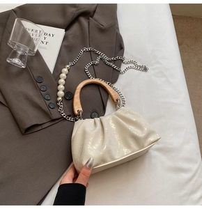 Détail du sac nuage plissé crème avec poignée en bois et grande chaîne en perles