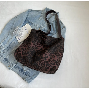 Detail of leopard print canvas bag draped over denim jacket with wide shoulder strap