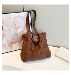 Detailed close-up of brown corduroy tote bag with embroidered red strawberries