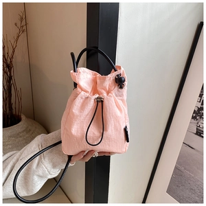 Close-up of pink drawstring mini bag featuring durable ripstop nylon and slim black strap