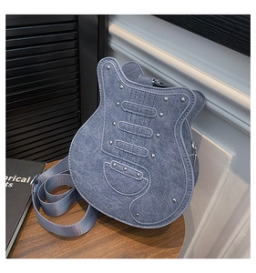 Detailed view of guitar shaped denim crossbody bag with silver rivets on a wooden table