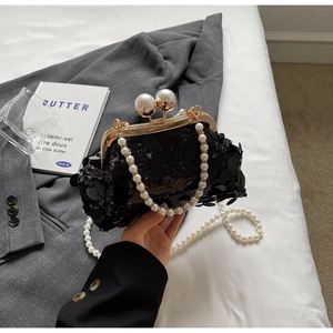 Detail of black sequin evening bag with gold metal frame and large pearl clasp accents