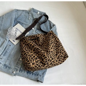 Detail of leopard print canvas tote bag with brown shoulder strap on denim jacket