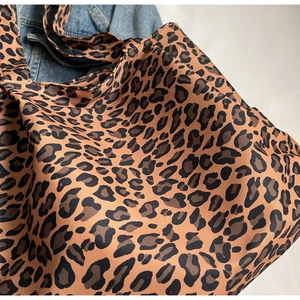 Close-up of leopard print canvas tote bag styled with denim jacket for casual look