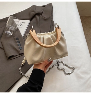 Détail du sac nuage plissé avec poignée en bois, chaîne argentée et perle décorative