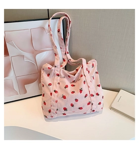 Detail of pink corduroy tote bag featuring red strawberry prints and soft texture