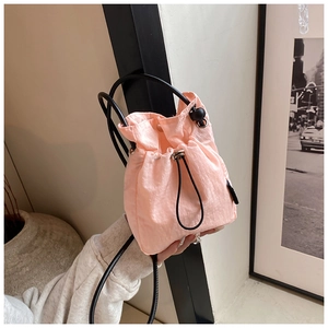 Detailed view of pink drawstring nylon bucket bag with textured fabric and thin black strap