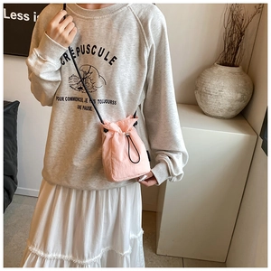 Detailed shot of a pink nylon drawstring mini crossbody bag worn by a model