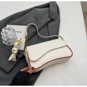 Detailopname van de crèmewitte baguette-tas met bruine contrastrand en goudkleurige hardware