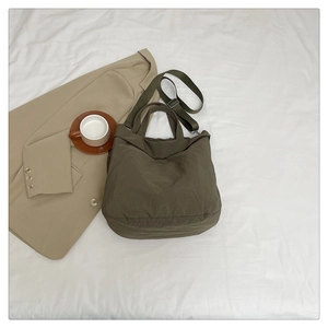 Détail du sac fourre-tout vert olive en nylon avec bandoulière large et anses