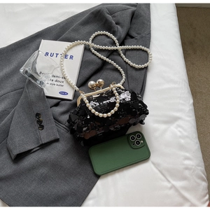 Detail of black sequin evening clutch with gold clasp and elegant pearl chain straps
