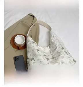 Détail du sac fourre-tout en toile à motif feuillage avec dentelle et poignée en cuir