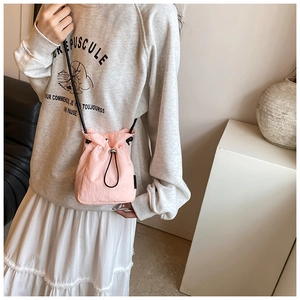 Detailed view of pink drawstring nylon crossbody bag with adjustable black strap