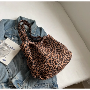 Detail of high-capacity leopard print tote bag placed with denim jacket on white bed