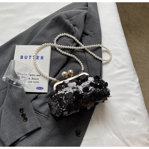 Detailed macro view of black sequin evening clutch bag with elegant white pearl strap