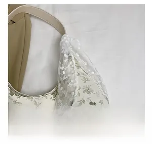 Détail du sac cabas en toile fleurie avec dentelle blanche et bandoulière beige