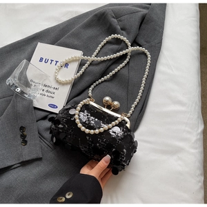 Detail of black sequin clutch with golden frame and elegant pearl clasp accents