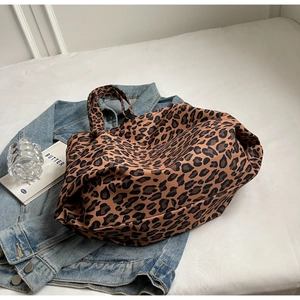 Detailed view of large leopard print tote bag on denim jacket and white sheets